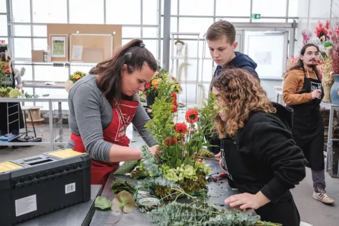 Deux jeunes en formation en train de créer un bouquet avec leur enseignante