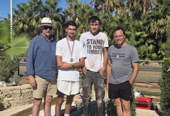 Adrien concourt pour la finale du MAF paysage. Il pose devant la scène paysagère qu'il a réalisé avec deux enseignants et Benjamin (lauréat du concours 2025)