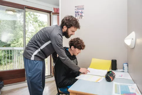 Un jeune du campus fait ses devoirs avec l'aide de son éducateur