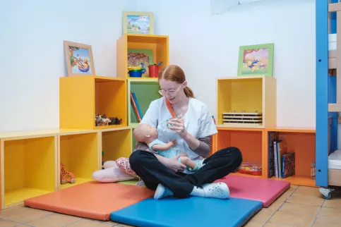 Une jeune en formation qui donne le biberon en salle de puériculture