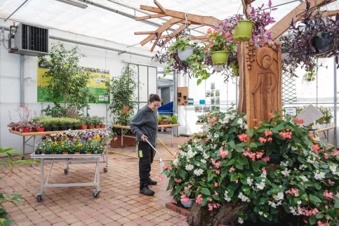 Une jeune en formation en train d'arroser les plantes dans les serres