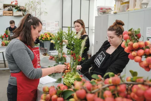 Deux jeunes en train de créer un bouquet avec leur enseignante