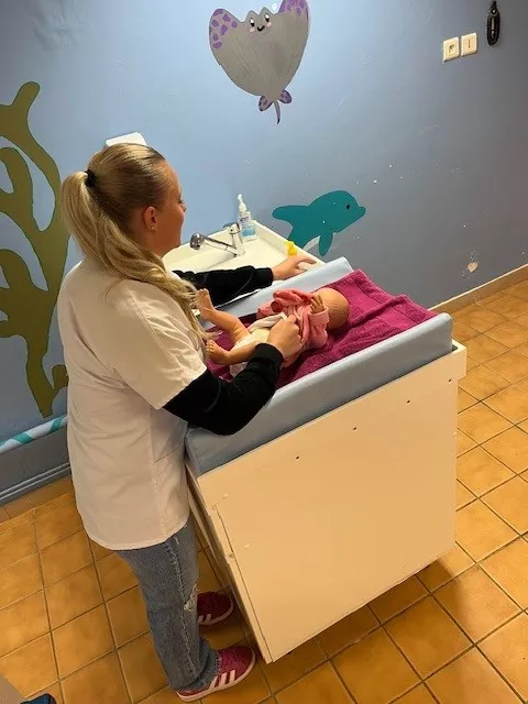Beverly change un bébé en salle de soins