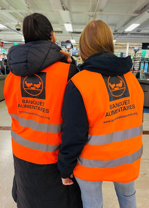 deux élèves sont de dos, on peut lire sur leur gilet orange "banque alimentaire"