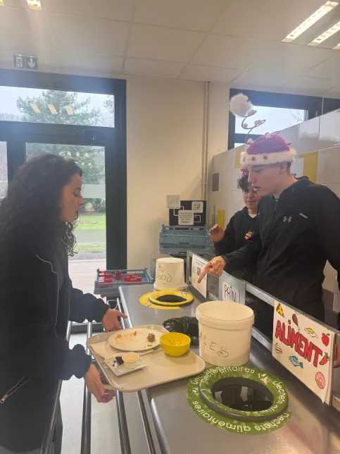 les jeunes, dans une ambiance festive et de Noel, sont à la cantine du Campus Saint-Antoine. Ils encouragent les personnes qui trient leurs déchets.