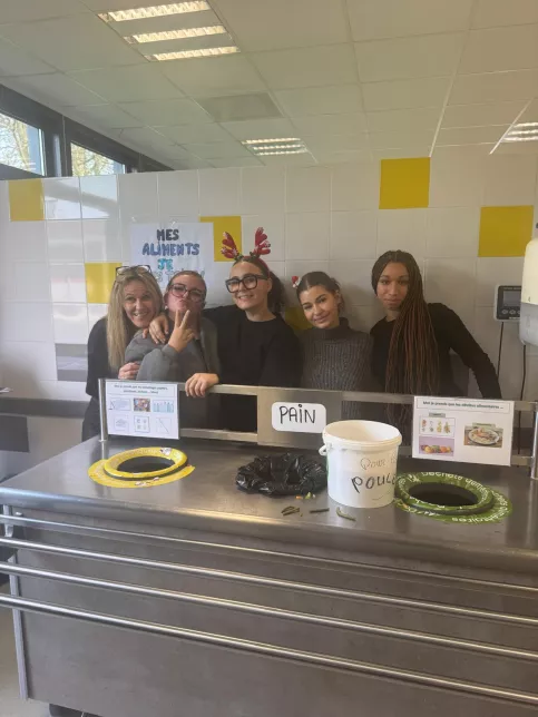 les jeunes, dans une ambiance festive et de Noel, sont à la cantine du Campus Saint-Antoine. Ils encouragent les personnes qui trient leurs déchets.