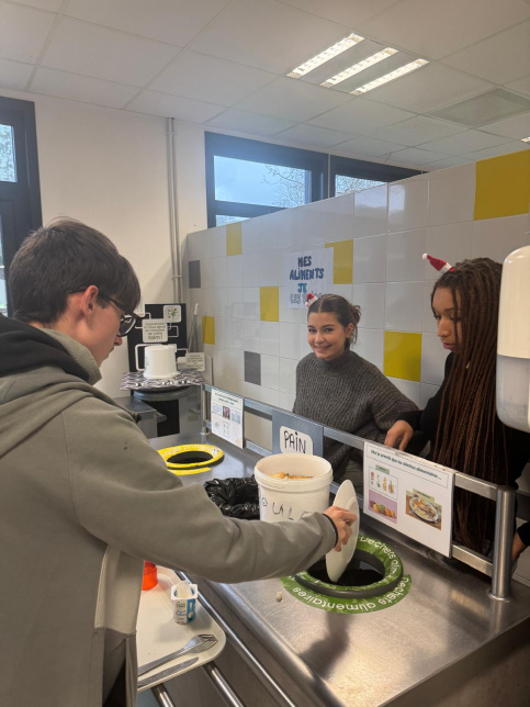 les jeunes, dans une ambiance festive et de Noel, sont à la cantine du Campus Saint-Antoine. Ils encouragent les personnes qui trient leurs déchets.