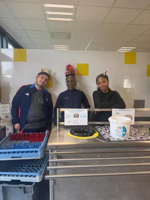 les jeunes, dans une ambiance festive et de Noel, sont à la cantine du Campus Saint-Antoine. Ils encouragent les personnes qui trient leurs déchets.