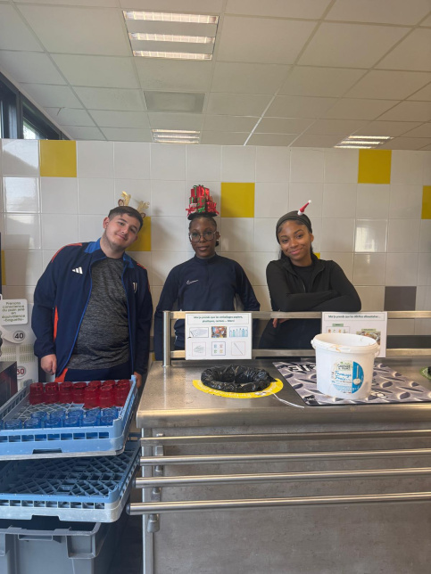 les jeunes, dans une ambiance festive et de Noel, sont à la cantine du Campus Saint-Antoine. Ils encouragent les personnes qui trient leurs déchets.