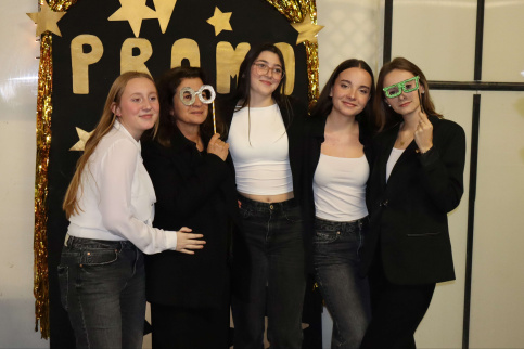 des jeunes et leur prof posent avec des déguisements devant une affiche promo2025 dans le cadre de la soirée de la réussite