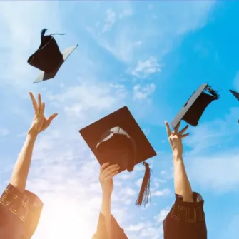 chapeau de jeunes diplomés lancés dans le ciel bleu