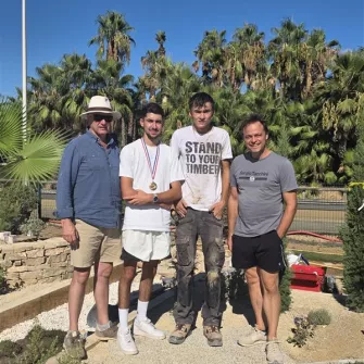 Adrien concourt pour la finale du MAF paysage. Il pose devant la scène paysagère qu'il a réalisé avec deux enseignants et Benjamin (lauréat du concours 2025)