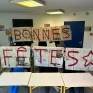 "Bonnes fêtes" est écrit sur des pages de journaux ouvertes tenues par des élèves